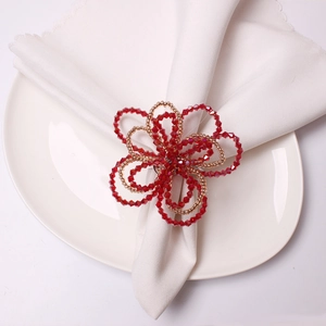 Red crystal beaded napkin ring in a flower shape on a white ceramic dining plate