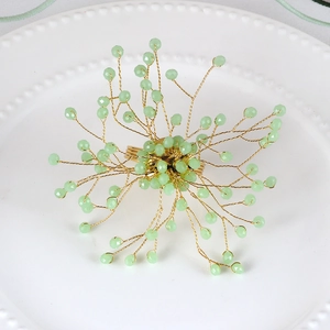 Macro view of a handmade gold wire napkin ring with faceted light green crystal beads