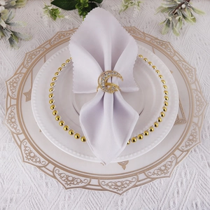 Elegant gold crescent moon and star napkin ring with crystals on white fabric