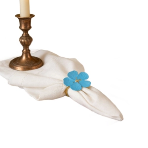 Light blue flower napkin ring with gold metal holder on a white fabric napkin