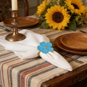 Detailed view of light blue flower napkin ring with gold center on a rustic table