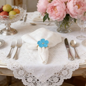 Light blue flower napkin ring with gold center on a white linen napkin for wedding table decor
