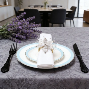 Detail of handcrafted white flower napkin ring with pearls and gold metal ring on a plate