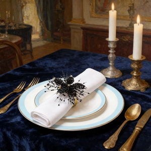 Detail of handcrafted black beaded flower napkin ring with gold buckle on luxury table