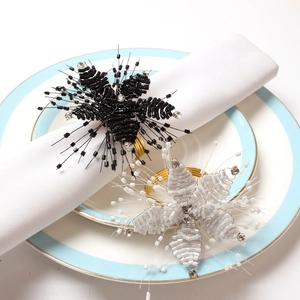 Detail of handmade beaded flower napkin rings with rhinestones on a white napkin