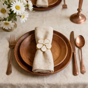 French cream flower napkin ring with gold edges on beige linen napkin on a table
