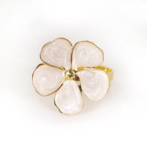 Macro shot of French cream floral napkin ring with pearl texture and golden metallic petals