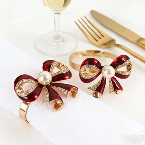Elegant red enamel bow napkin rings with gold trim and central pearl for table decor