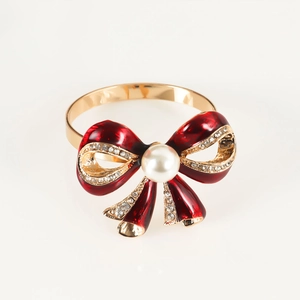 Detail of golden bow napkin ring with red enamel, center pearl, and sparkling rhinestones