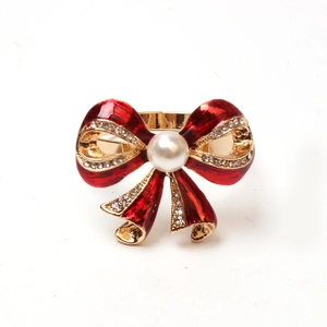 Close-up of red enamel bow brooch with sparkling rhinestones and center pearl accent