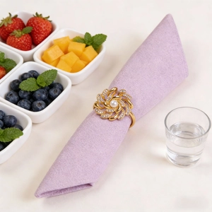 Detail of floral gold napkin ring with white pearls and rhinestones on a purple napkin
