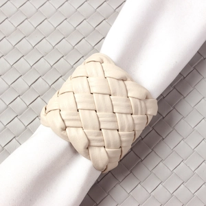 Macro shot of beige woven leather napkin ring showcasing intricate cross-stitch craftsmanship