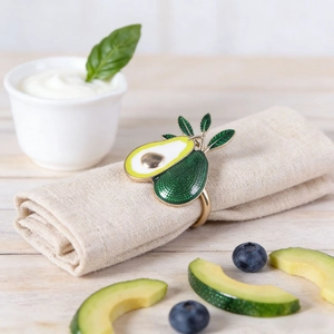 Portatovagliolo creativo ad avocado con anello in metallo dorato su tavola rustica