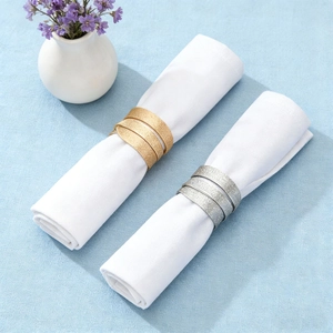 Modern gold and silver spiral napkin rings with a frosted finish on white linens