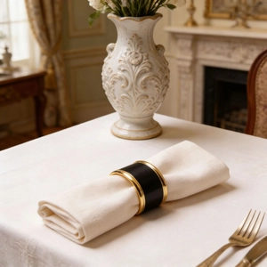 Detail of black napkin ring with gold edges on white fabric in a luxury dining setting