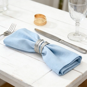 Modern spiral sand-gold and silver frosted metal napkin rings on a light blue napkin