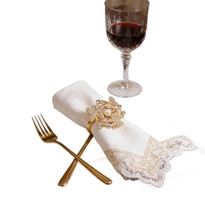 Golden flower napkin ring with rhinestones and pearl on a formal dining table