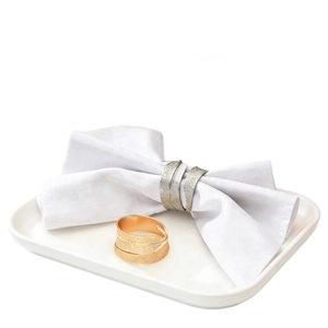 Elegant sand gold and silver napkin rings with frosted texture on white dinner plate