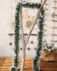 Détail de guirlande de Noël enneigée vert foncé avec nœuds argentés sur une branche