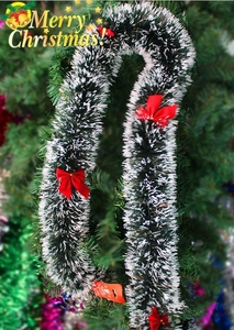 Guirlande de Noël vert foncé avec pointes blanches et nœuds rouges sur le sapin