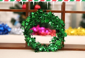 Detail of 7.5m green Christmas star garland with metallic tinsel sequins on a wooden grid