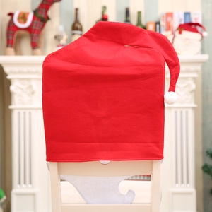 Housses de chaise bonnet de Noël rouge avec pompon blanc dans un décor de fête chaleureux