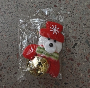 Dettaglio dell'orso natalizio con campanello d'oro in confezione trasparente
