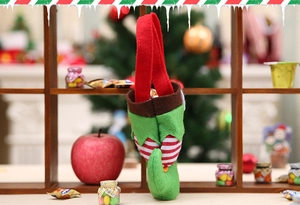 Detail of elf boot Christmas candy bag made of felt fabric with red stripes on wooden shelf