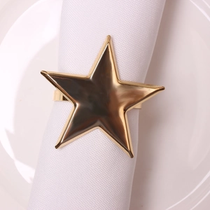 Glossy gold pentagram star napkin ring on a white cloth napkin with a ceramic plate