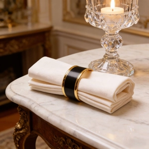Elegant black enamel napkin ring with gold metal trim on a white napkin surface