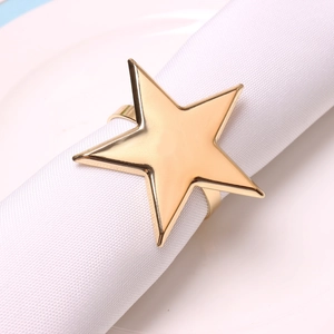Macro shot of polished gold star napkin ring showing glossy metal finish on white linen
