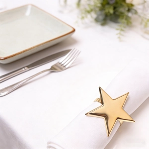 Polished gold star-shaped napkin ring on a white cloth for elegant table decoration