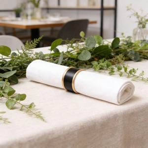 Nordic style black leather napkin ring with gold metal trim on white linen cloth