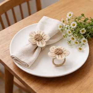 Handmade raffia sunflower napkin rings on white ceramic plate with rustic wood background