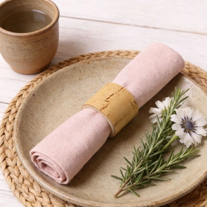 Handcrafted bamboo napkin ring with pink fabric cloth on a rustic ceramic plate