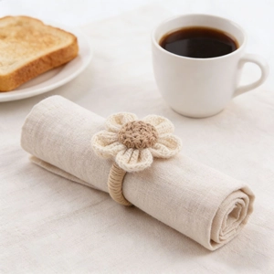 Close-up of handmade raffia sunflower napkin ring on beige linen napkin tabletop