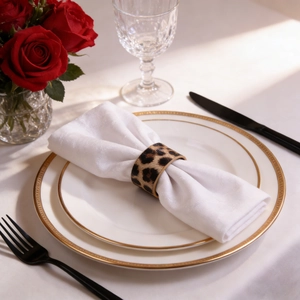 Close-up of leopard print leather napkin ring on a white cloth napkin in a luxury setting