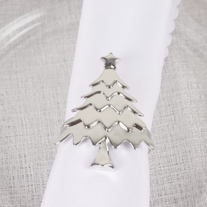 Close-up of polished silver Christmas tree napkin ring with star top on linen cloth