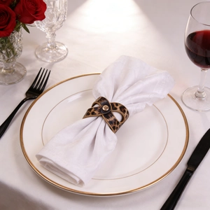 Close-up of leopard print leather napkin ring with golden metal clasp on a formal dinner table