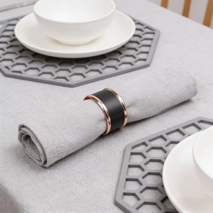 Close-up of black Nordic napkin ring with rose gold metal trim on grey linen fabric