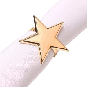 Polished gold pentagram star napkin ring holder with shiny metal finish on white linen