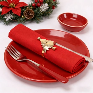 Close-up of golden Christmas tree napkin ring on a festive red holiday dinner plate