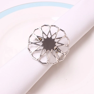 Detailed view of silver hollow flower napkin ring on a white cloth on a ceramic plate