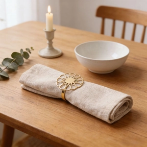 Golden geometric hollow sunflower napkin ring with beige linen cloth on wooden table