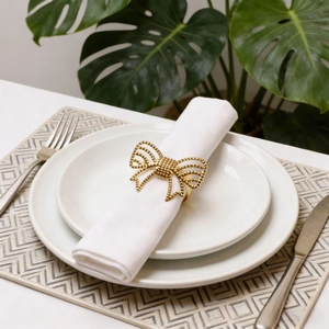 Elegant gold hollow butterfly napkin ring with beaded texture on a white cloth napkin