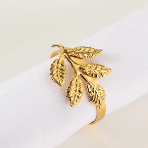 Close-up of golden leaf napkin ring showing detailed vein textures on white fabric