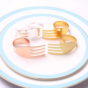 Detail view of four creative fork-shaped napkin rings in gold, silver, and rose gold