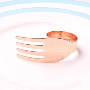 Detailed view of creative rose gold fork-shaped napkin ring on a white plate