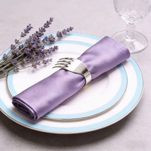 Polished silver fork-shaped napkin ring with lavender napkin on elegant white dinner plate