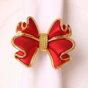 Détail du rond de serviette nœud rouge et doré sur une serviette blanche